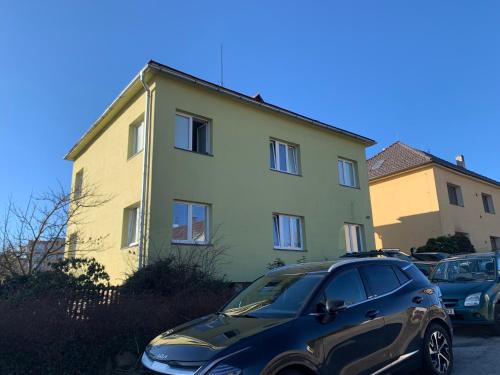 a car parked in front of a yellow building at Apartman Slonek in Nové Město na Moravě