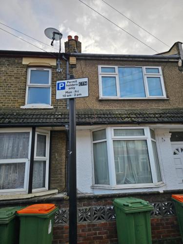 a parking sign in front of a house with two trash cans at Umbrella Properties London Excel in London