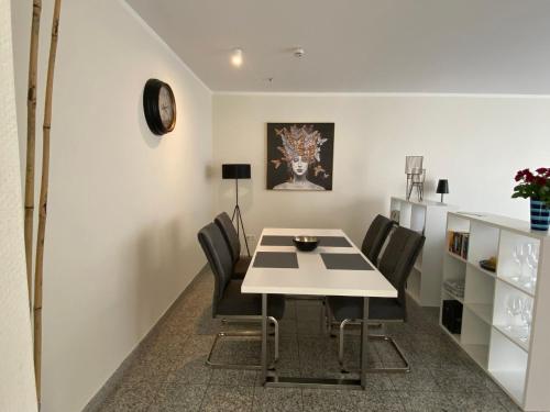 uma sala de jantar com uma mesa branca e cadeiras pretas em strandnahe FeWo mit Schwimmbad im Haus, a cappella 03, Binz em Binz