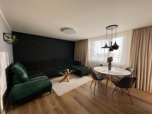 Apartmán Olívia في شامورين: غرفة معيشة مع أريكة خضراء وطاولة