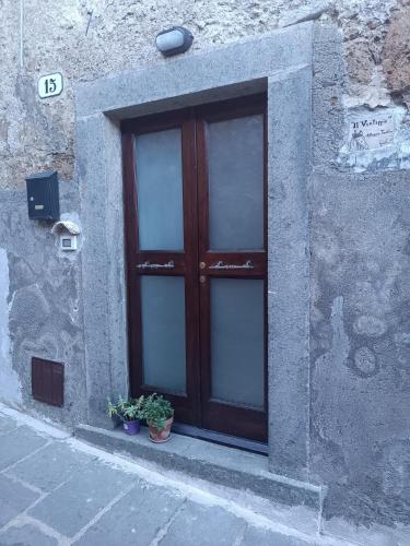 una finestra in un edificio in pietra con due piante in vaso di Il Vantaggio a Bagnoregio