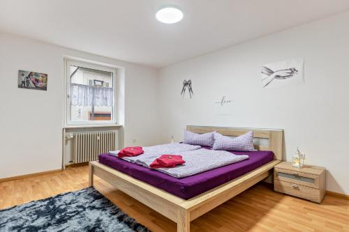 een slaapkamer met een bed met paarse lakens en een raam bij Ferienwohnung Joanna in Wolfach
