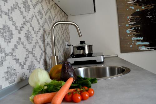 a kitchen counter with carrots and vegetables on a sink at Aura Mura in Peschiera del Garda