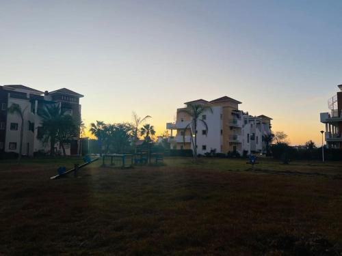 a park with a playground in front of some buildings at SAIDIA AP4 cosy avec piscine in Saidia 
