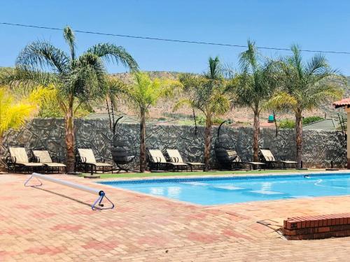 a swimming pool with lounge chairs and palm trees at Mohlaletse Guest House in Ga-Matsi