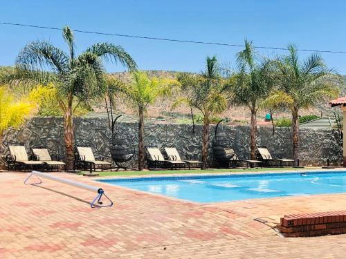 una piscina con tumbonas y palmeras en Mohlaletse Guest House en Ga-Matsi