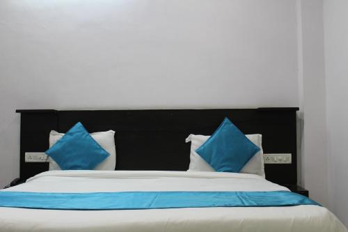 a bed with blue and white pillows on it at Hotel Quality Time in Udaipur