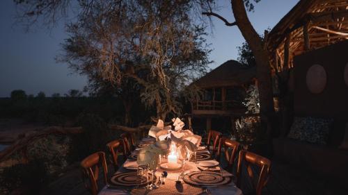 a long table with candles and chairs at night at Mashatu Lodge in Lentswelemoriti