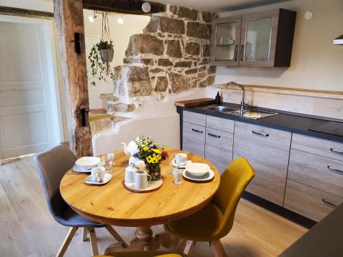 eine Küche mit einem Holztisch mit Stühlen und einem Waschbecken in der Unterkunft Donauwelle in Sigmaringendorf