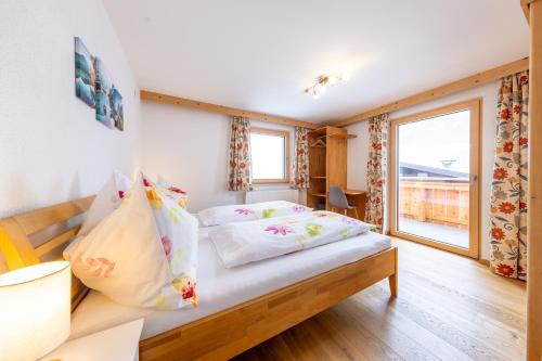 um quarto com uma cama e uma grande janela em Ferienwohnung Gipfelreich em Bramberg am Wildkogel