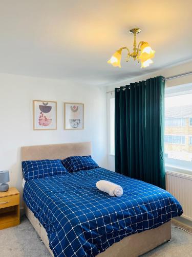 um quarto com uma cama com um cobertor xadrez azul em Sittingbourne, Kent em Kent