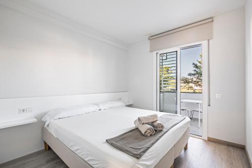 een witte slaapkamer met een bed en een balkon bij Tango in Sitges