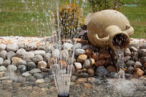 a water fountain in a garden with rocks and a statue at Hotel La Ruota in Pianfei