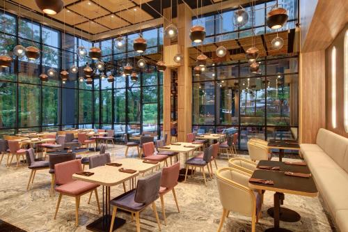 - un restaurant avec des tables, des chaises et de grandes fenêtres dans l'établissement ibis Styles Serpong BSD City, à Tangerang