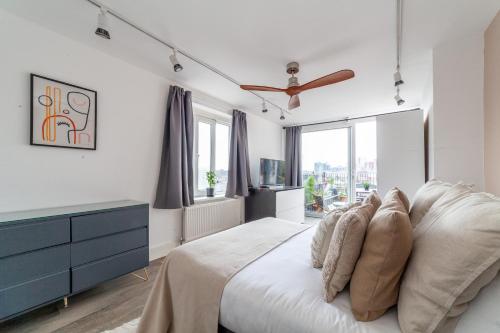 a bedroom with a bed with a blue dresser and windows at The Nine Elms Collection in London