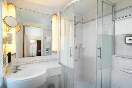 a bathroom with a sink and a shower at Leonardo Hotel Berlin KU'DAMM in Berlin