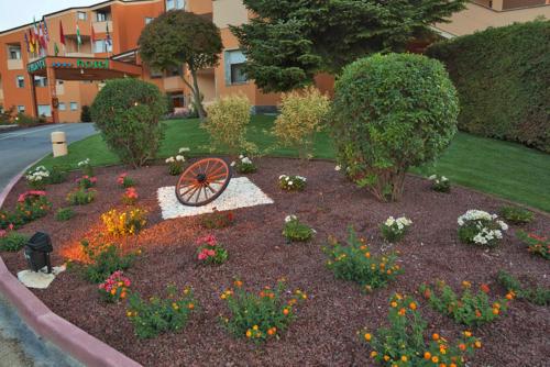 a garden with flowers and a wheel in the middle at Hotel La Ruota in Pianfei