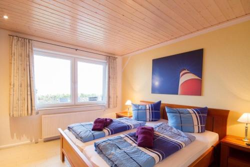 two beds in a room with a large window at Haus Halligenblick Amrum in Wittdün