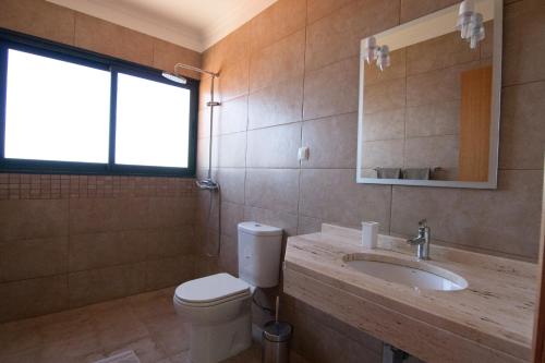 een badkamer met een toilet, een wastafel en een spiegel bij Casa Nici in Calheta