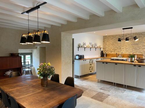 una cucina e una sala da pranzo con un tavolo di legno di Maison Marguerite, Maison de Charme,jacuzzi a Gigny