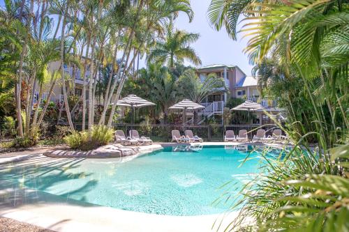 a swimming pool with chairs and umbrellas at Sandy Beach Resort in Noosaville