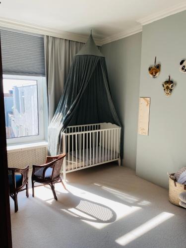 a baby crib with a canopy in a room at Familiehuis aan zee met ruim dakterras in Zandvoort