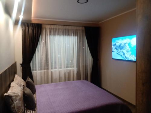 1 dormitorio con 1 cama y TV en la pared en Кръчмъ При Байката апарт, en Teteven