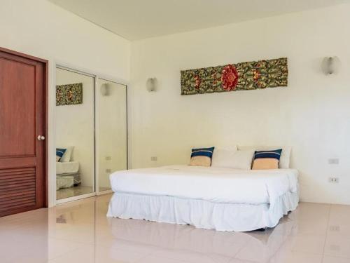 a white bedroom with a large bed and a mirror at Am Samui Resort Taling Ngam in Taling Ngam Beach