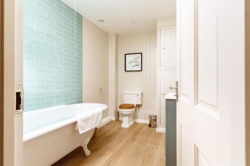 a bathroom with a bath tub and a toilet at Gatehouse North in Worstead