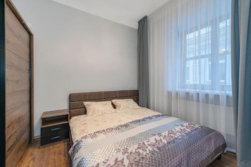 a bedroom with a bed and a large window at Old town apartment with free parking by Polo Apartments in Kaunas