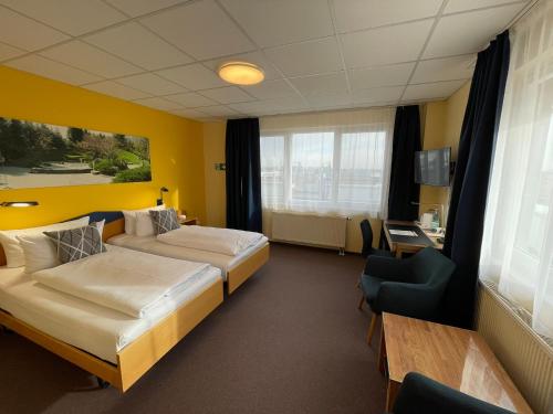 a hotel room with two beds and a desk at Parkhotel Marzahn in Berlin