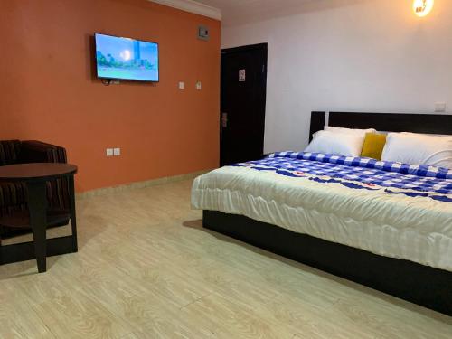 ein Schlafzimmer mit einem Bett und einem TV an der Wand in der Unterkunft BOSS HOTELS & SUITES in Lagos