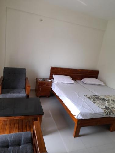 1 dormitorio con 1 cama y 1 silla en APPLE APPARTMENT, en Kāladi