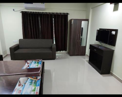 sala de estar con sofá y TV en APPLE APPARTMENT, en Kāladi