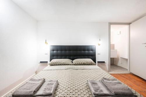 een slaapkamer met een groot bed met een zwart hoofdeinde bij Appartamento al centro di Cagliari (Marina) in Cagliari