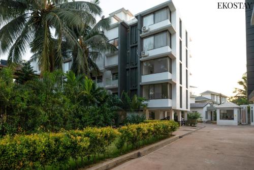 a building with palm trees in front of it at EKOSTAY - Bliss Apartment in Candolim