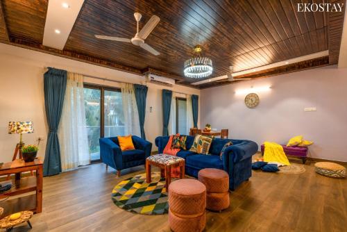 a living room with blue couches and a wooden ceiling at EKOSTAY - Bliss Apartment in Candolim
