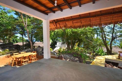 eine Terrasse mit einem Tisch, Stühlen und Bäumen in der Unterkunft Eco Lodge Cristal Nosy Komba in Nosy Komba