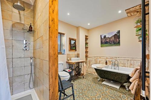 a bathroom with a tub and a toilet at Finest Retreats - The Old Smithy in Belchford