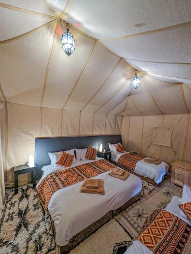 a bedroom with two beds in a tent at Camel Luxury Camp in Merzouga