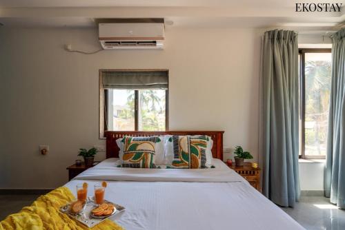 a bedroom with a large white bed and a window at EKOSTAY - Bliss Apartment in Candolim