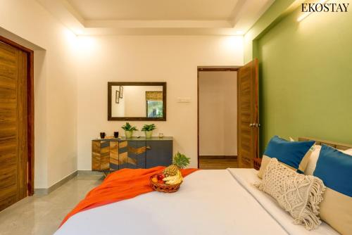 a bedroom with a large bed with an orange blanket at EKOSTAY - Bliss Apartment in Candolim
