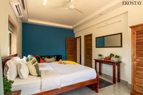 a bedroom with a bed with a blue accent wall at EKOSTAY - Bliss Apartment in Candolim