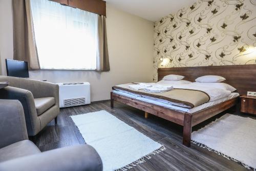 a bedroom with a bed and a couch and a window at Gránátalma Vendégház in Fehérvárcsurgó