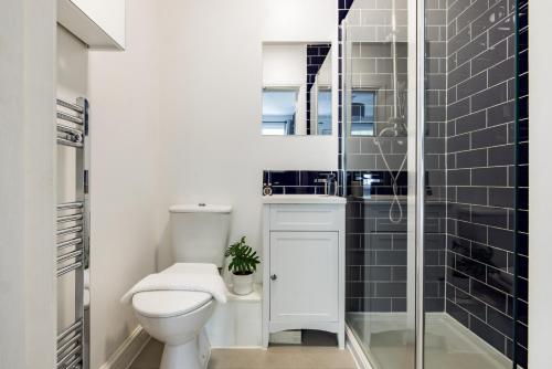 a bathroom with a toilet and a glass shower at The Stratford Villas in London