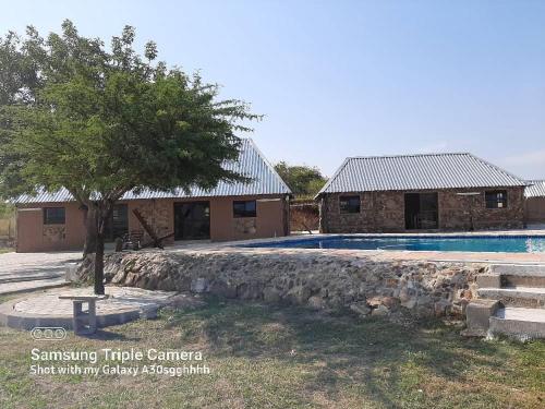 una casa con piscina y un árbol en Inkwazi Getaway Lodge en Manzini
