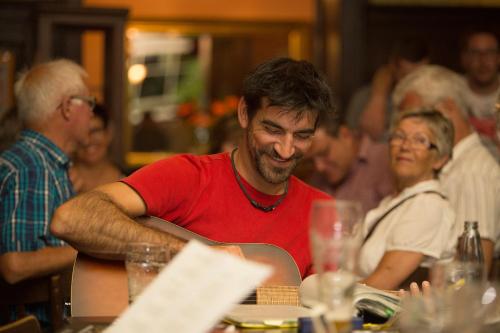a man sitting at a table with a guitar at Hajo´s Germania Lodge & Irish Pub in Rüdesheim am Rhein