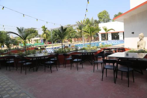 a patio with tables and chairs and a pool at Suryaansh in Pālghar