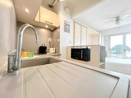 cocina con fregadero y microondas en Le Dulys : Apt 2 prs, vue mer, clim, 2 min plages en Antibes