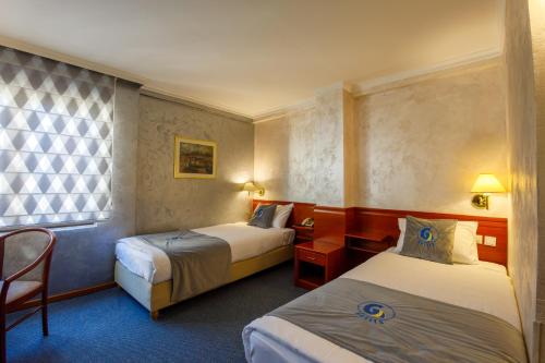 een hotelkamer met 2 bedden en een raam bij Skopje G Hotels in Skopje